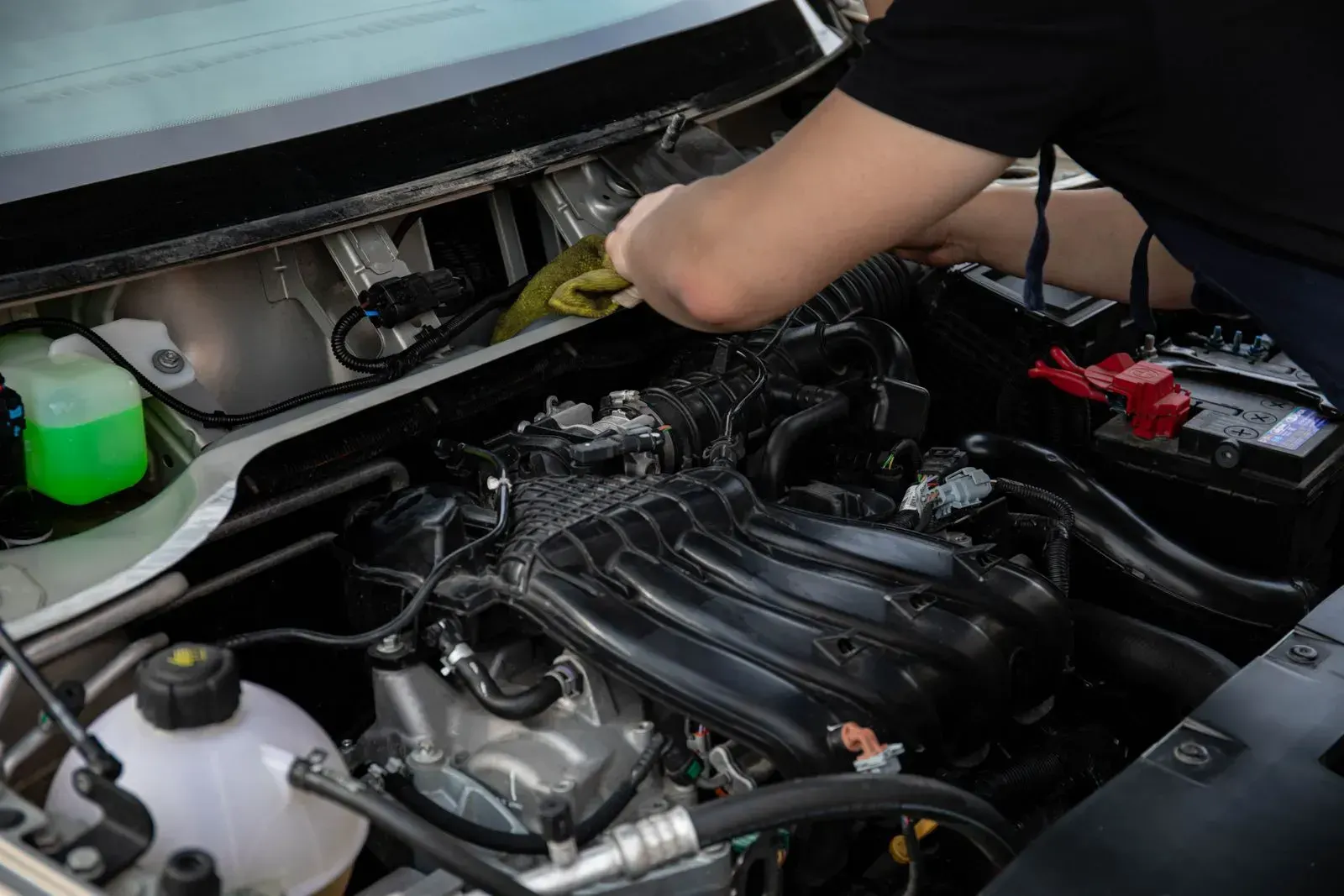 Hands working over an open engine bay, wiping down a fitting.